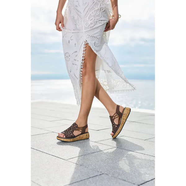 Rieker V1765-24 ladies wide fit brown elasticated sandals with open back and cork platform sole, worn by a woman outdoors.