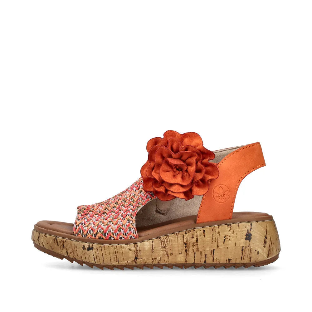 Rieker V1783-90 women's orange textile slide sandals with side zip, large fabric flower decoration, cork wedge sole, and supportive strap.