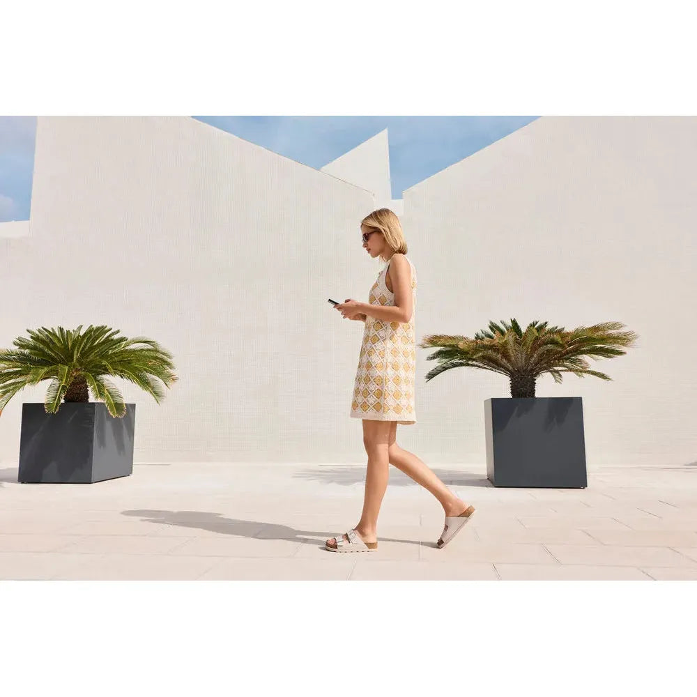 Rieker V3190-40 ladies off-white leather buckle mules, stylish and comfortable summer footwear, outdoor scene with modern architecture.