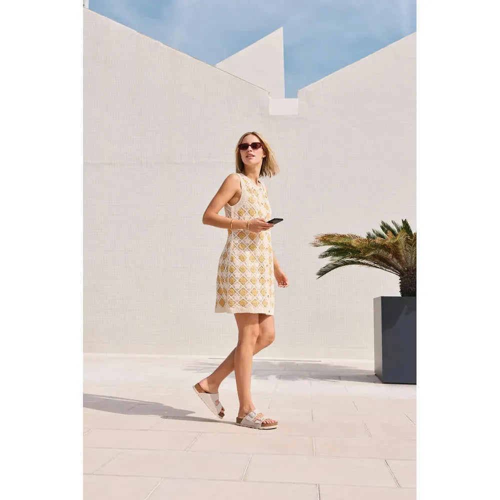 Rieker V3190-40 women's off-white leather buckle mules on a sunny outdoor setting with modern white walls.