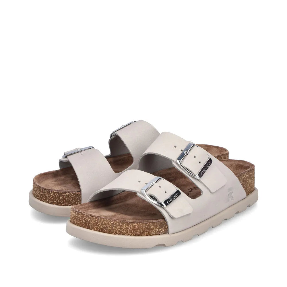 Rieker V3190-40 women's off-white leather slip-on mule sandals with buckle straps and cork footbed.