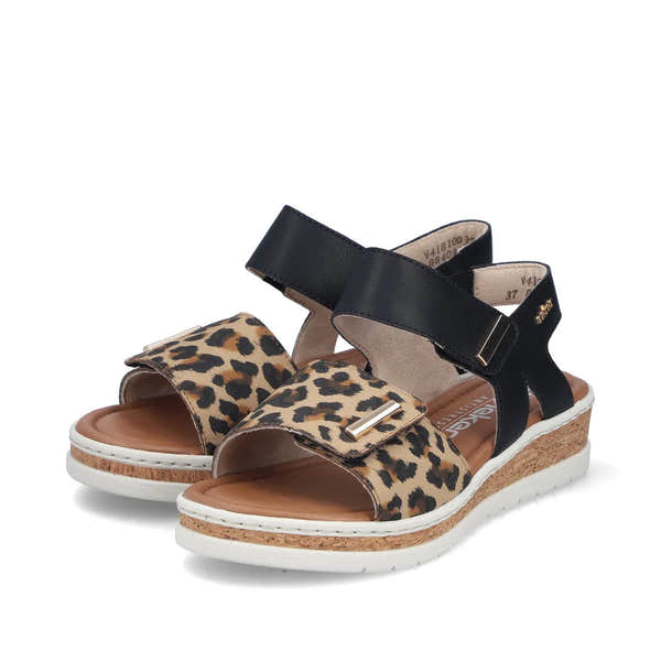 Rieker V4181-00 women's wide-fit sandals with leopard print front strap, black touch-fastening ankle straps, cork wedge heel, and white sole.