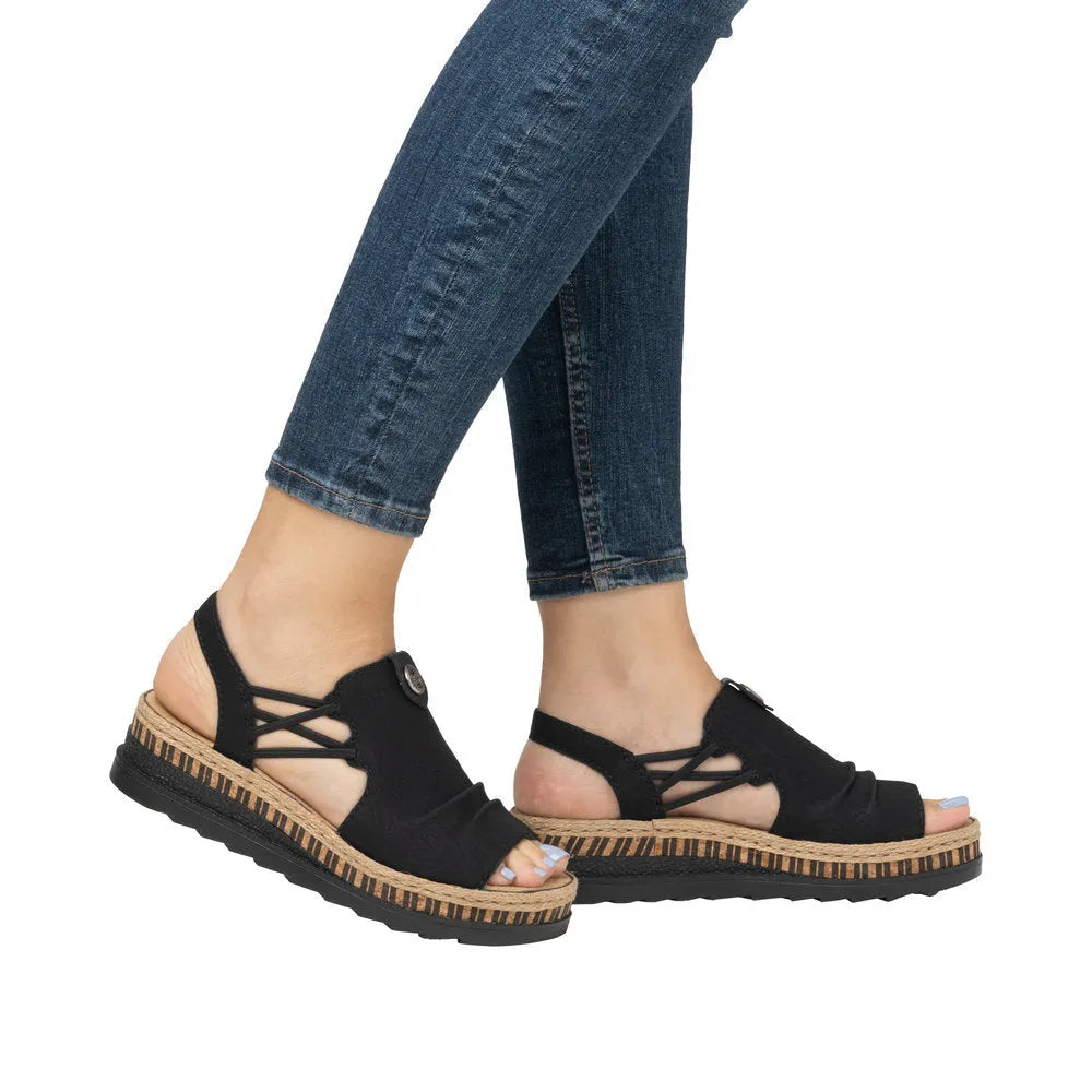 Rieker V7972-00 black slip-on sandals with woven heel detail, open toes, elastic straps, and a chunky sole.