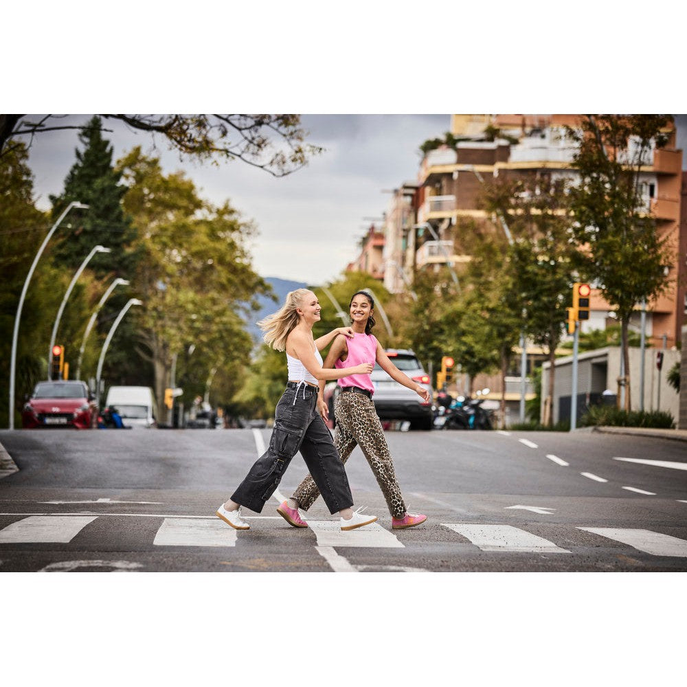 Rieker W1202-82 Ladies White/Metallic Leather Lace-Up Trainers on women walking across street in city setting.