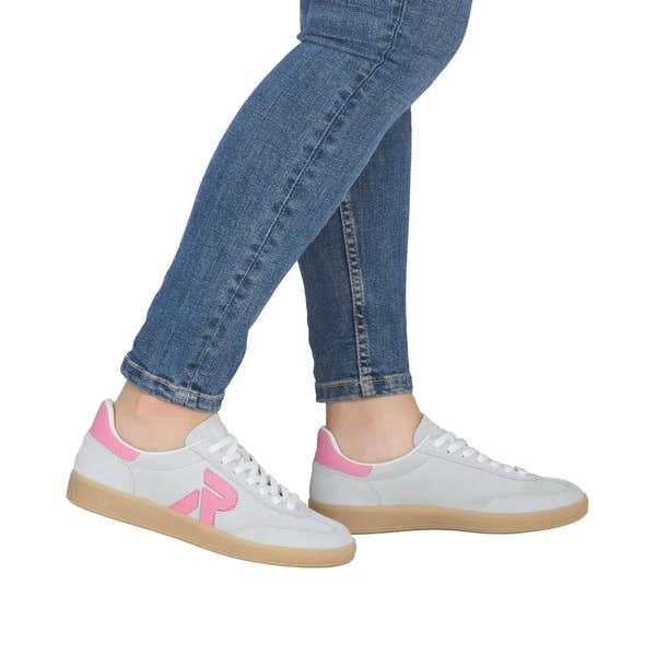 White and pink suede lace-up trainers with beige soles, worn with blue jeans.