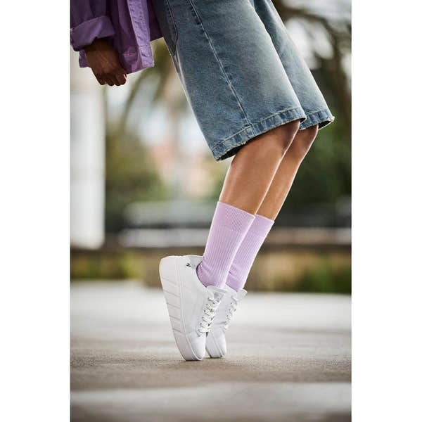 Rieker W2601-80 women's white leather lace-up trainers with chunky sole, paired with pastel purple socks, casual outdoor footwear.