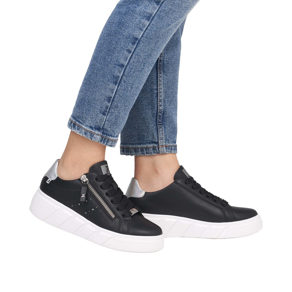 Rieker W2605-00 women's black leather sneakers with zip and lace-up closure, white sole, and metallic accents.