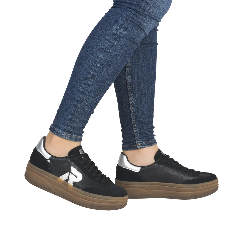 Rieker W3700-00 women's black leather lace-up trainers with silver accents and thick tan sole.