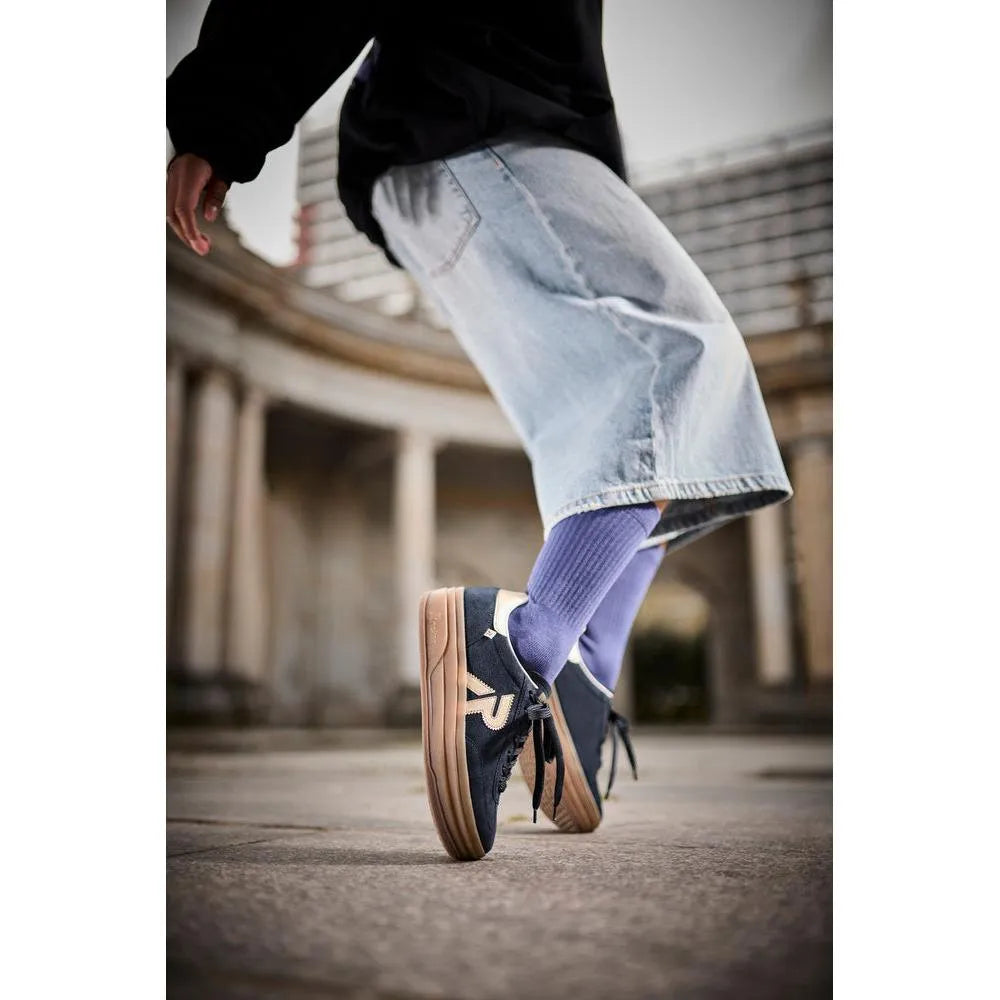 Rieker W3700-14 ladies blue suede lace-up trainers, stylish casual shoes with beige gum soles and purple socks, urban background.