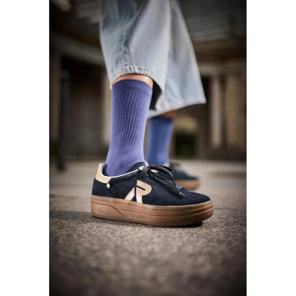 Rieker W3700-14 women's blue suede lace-up trainers with beige accents and thick brown sole, worn with purple socks and jeans.