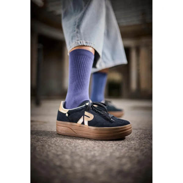 Rieker W3700-14 women's blue suede lace-up trainers with beige accents and thick brown sole, worn with purple socks and jeans.
