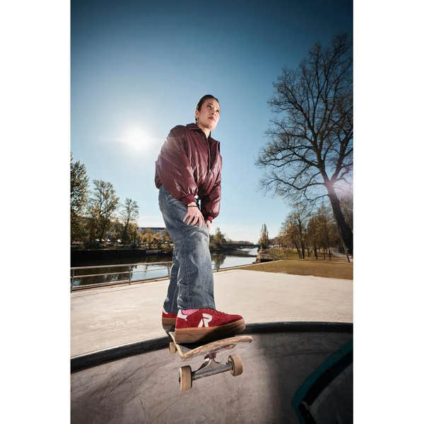 Rieker W3700-35 women's red suede lace-up trainers, sporty casual sneakers, outdoor skating scene, sunny day with trees.