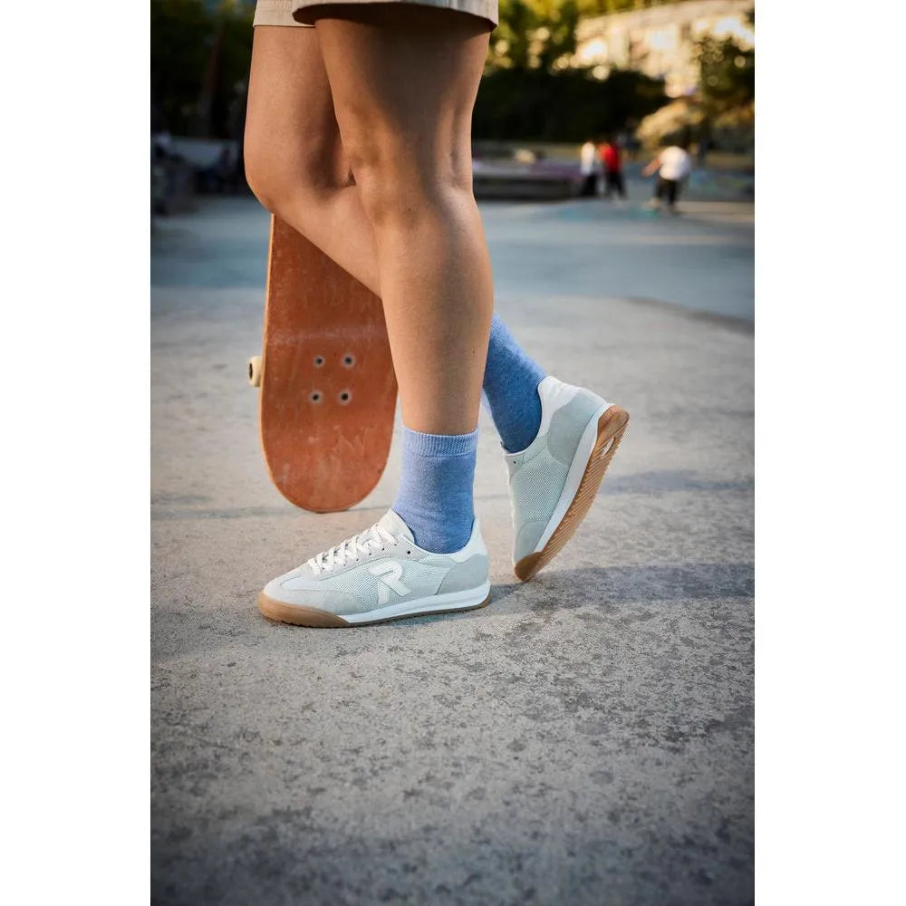 Rieker W4000-52 mint suede and textile lace-up trainers, with gum sole, worn with blue socks, outdoors on pavement.