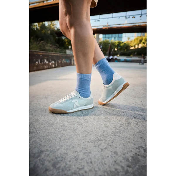 Rieker W4000-52 mint suede and textile lace-up trainers with white accents, worn with blue socks outdoors.