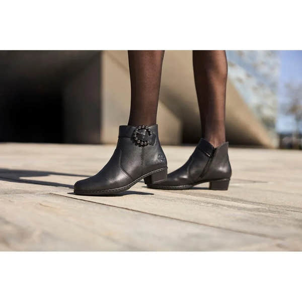 Rieker Y0797-00 women's black leather ankle boots with side zips and decorative buckle detail.