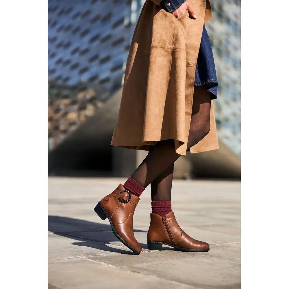 Rieker Y0797-24 women's brown leather ankle boots with side zipper, low heel, stylish design, worn with black tights and maroon socks.