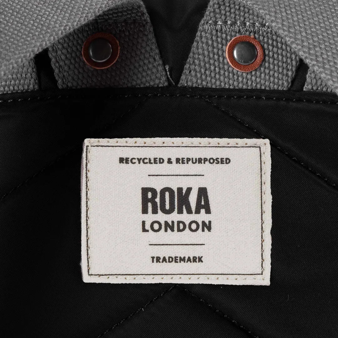 Roka Bantry B Black recycled nylon jacket detail with label, grey textured collar, and metal/button accents.