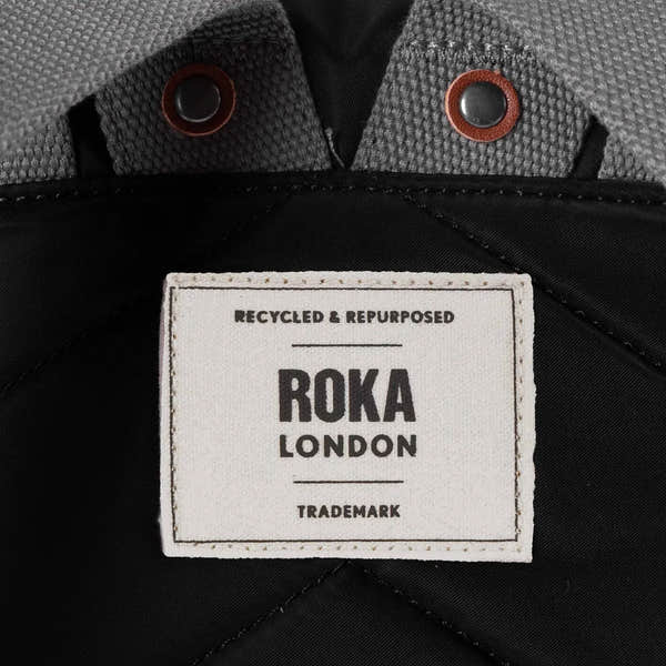 Roka Bantry B Black recycled nylon jacket detail with label, grey textured collar, and metal/button accents.
