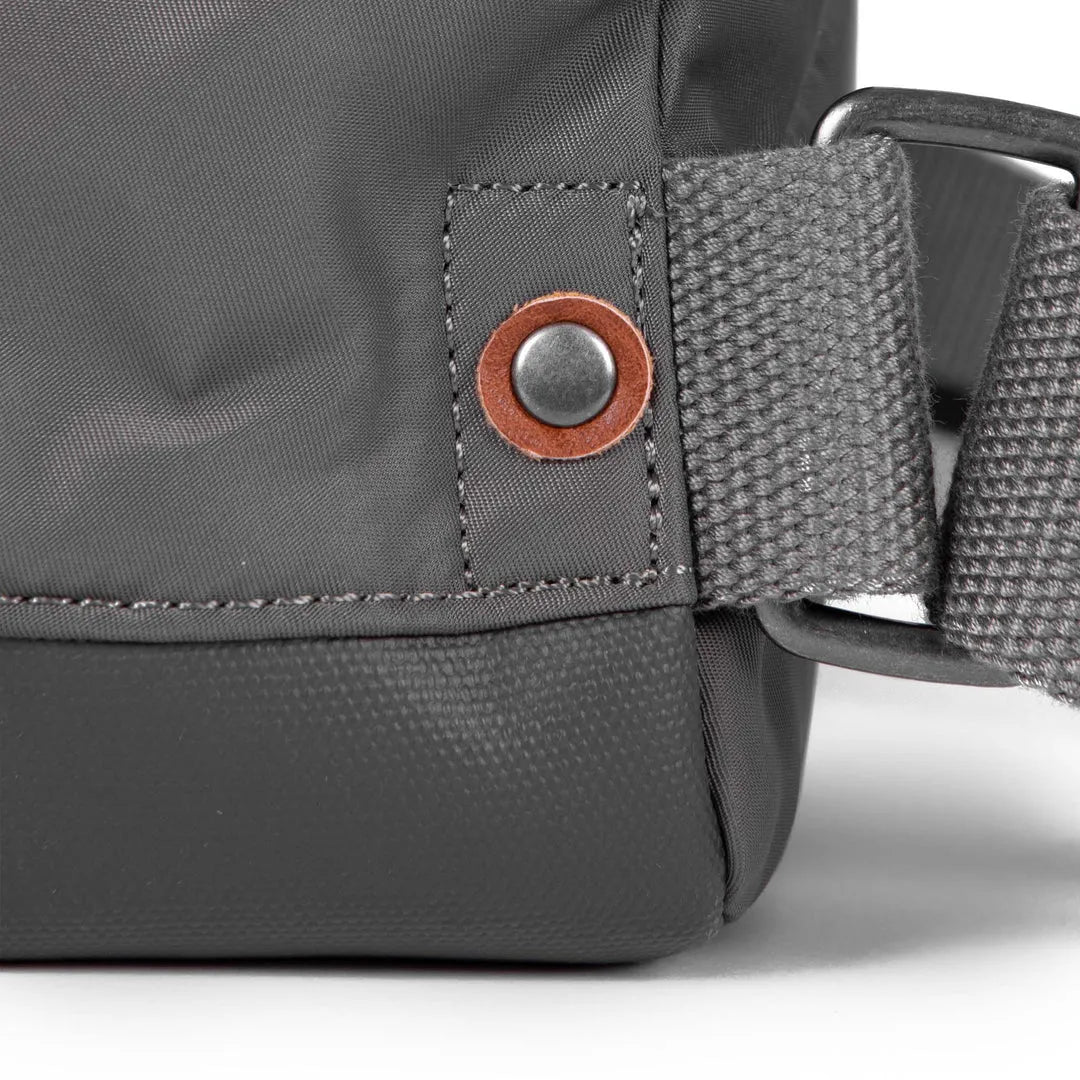 Roka Bantry B Graphite recycled nylon backpack with metal rivet and adjustable gray strap.