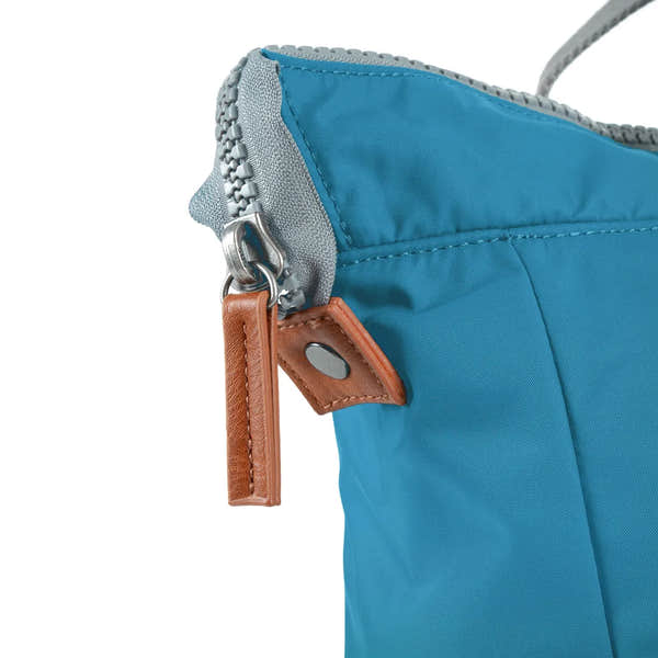 Close-up of Roka Bantry B Marine recycled nylon lightweight boat bag with leather detail, blue fabric, silver zipper, and attachment hardware.