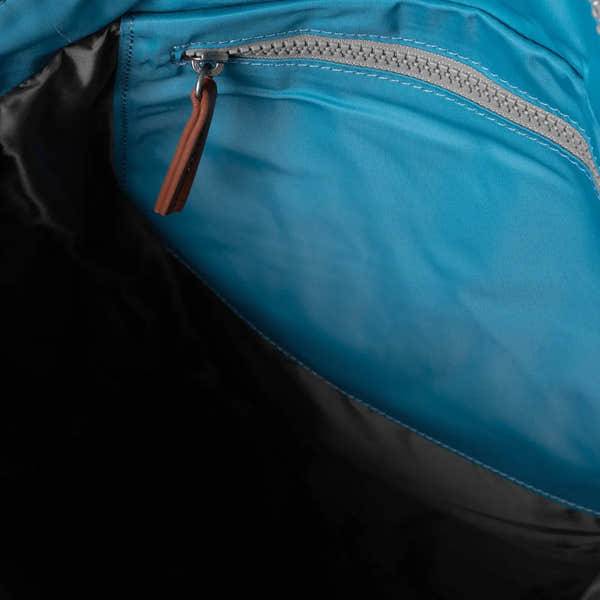 Roka Bantry B backpack made from recycled nylon, featuring a blue fabric with a zippered pocket and brown zipper pull.