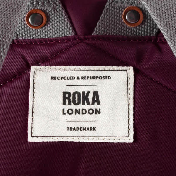 Roka Bantry B Plum Recycled Nylon jacket with label, burgundy interior, gray textured shoulder, and button details.