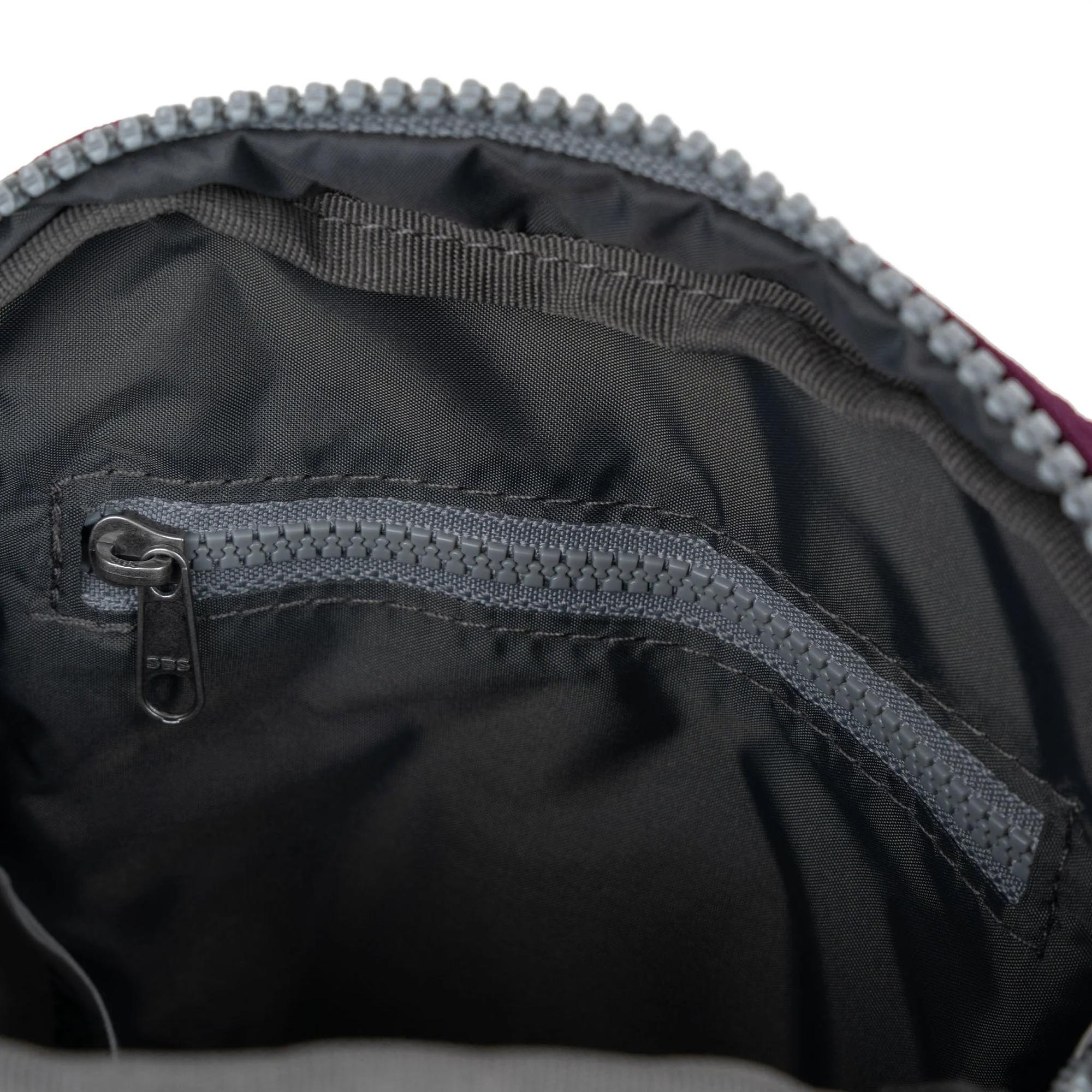 Interior of Roka Bond Cherry Lacquer Recycled Canvas bag with zippered pocket and black fabric lining.