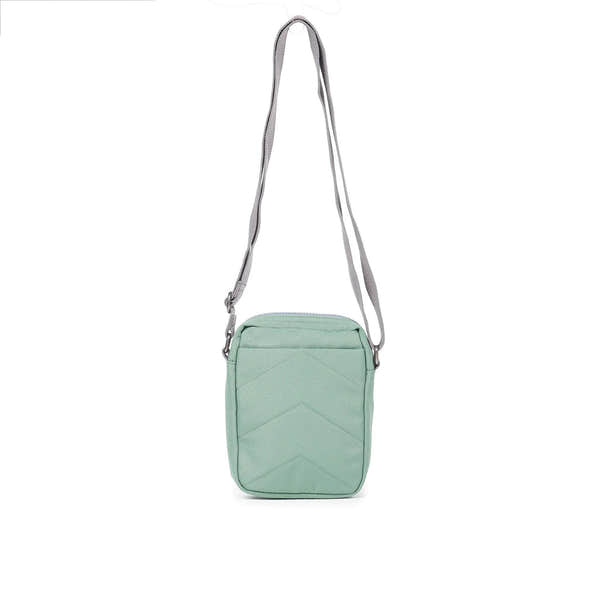 Roka Bond Frost recycled canvas crossbody bag, one size, light green with four chevron-stitched panels and adjustable gray strap.