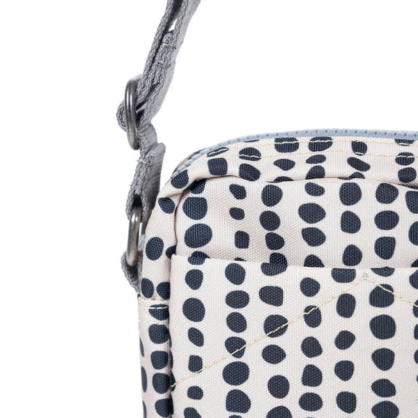 Close-up of Roka Bond linear dot recycled canvas bag with adjustable strap, navy polka dot pattern, and metal hardware.