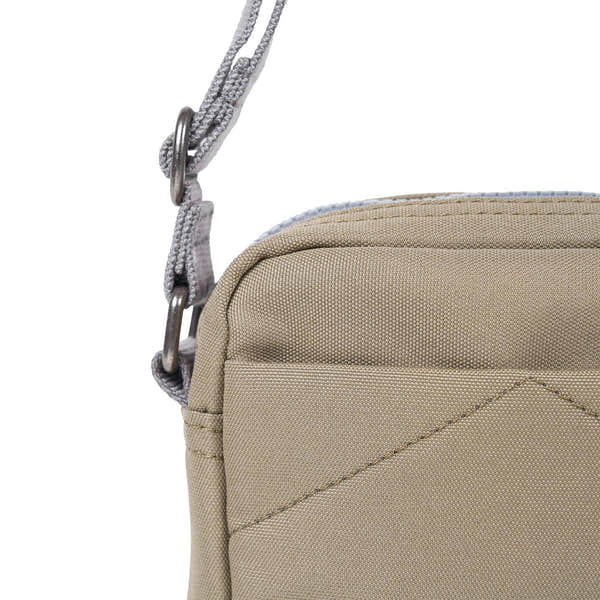 Roka Bond Taupe recycled canvas crossbody bag with adjustable gray strap, one size, close-up of top corner and stitching.