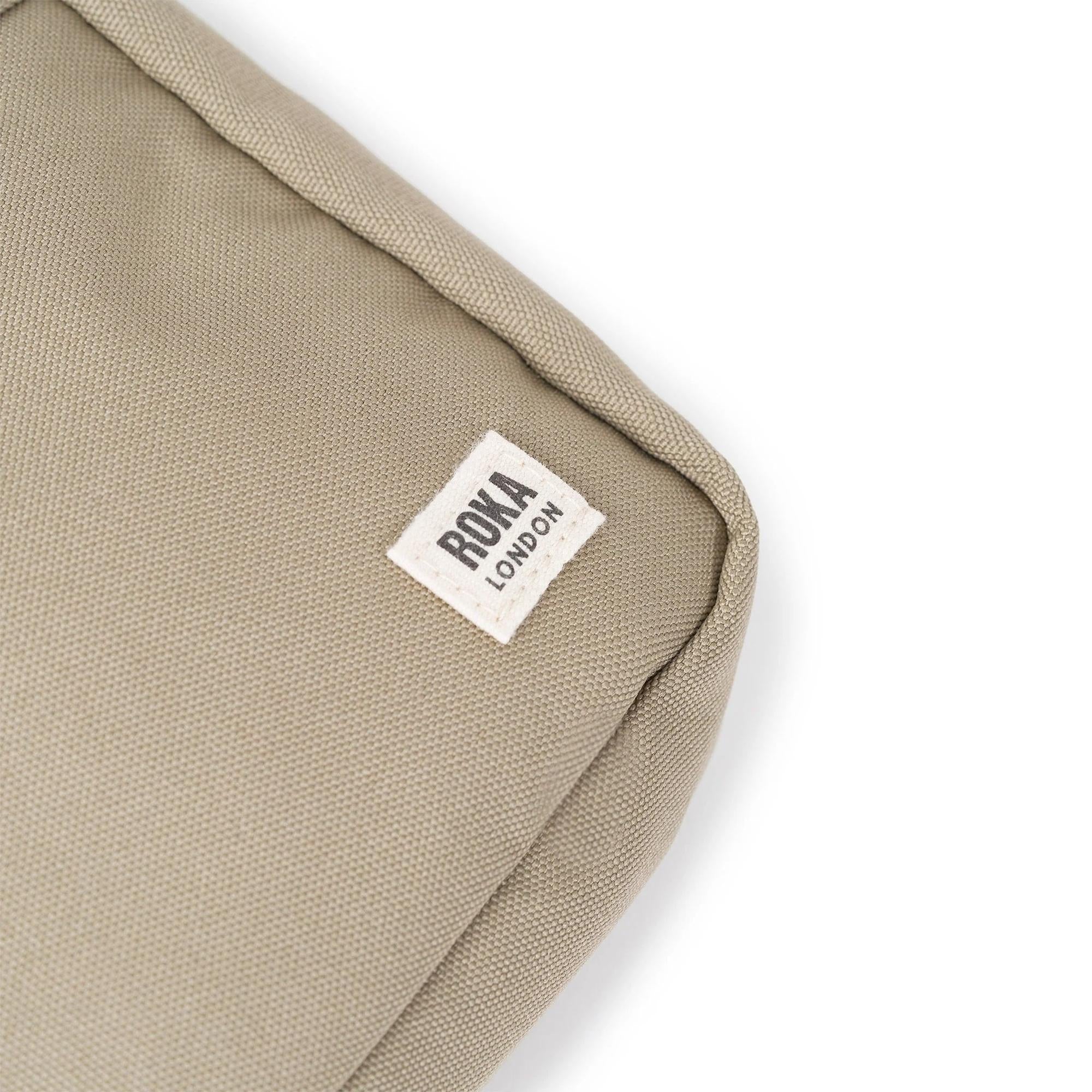 Roka Bond Taupe Recycled Canvas Bag, one size, minimal design, close-up of brand label on textured taupe fabric.
