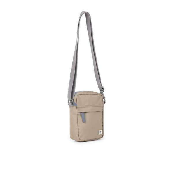 Roka Bond taupe recycled canvas crossbody bag with adjustable strap, front zipper pocket, and compact design.