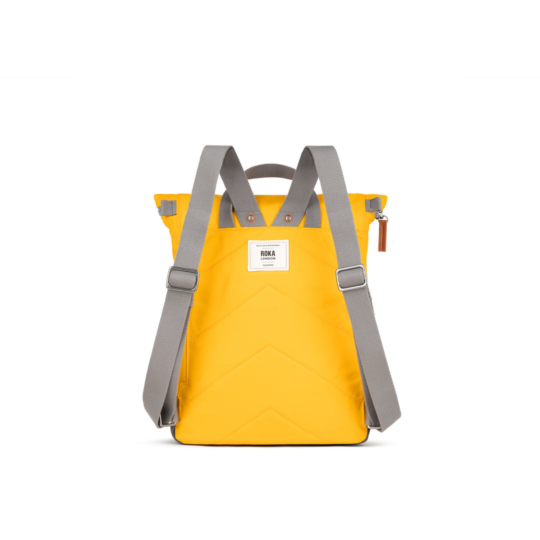 Yellow Roka Canfield backpack made from recycled nylon with gray adjustable shoulder straps and a white brand label.