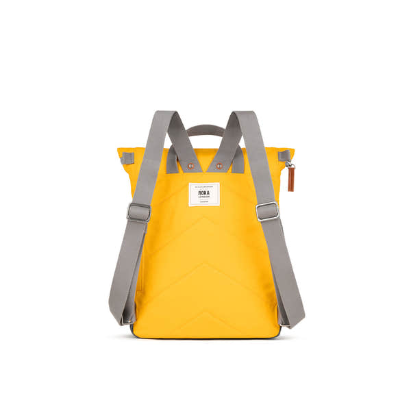 Yellow Roka Canfield backpack made from recycled nylon with gray adjustable shoulder straps and a white brand label.