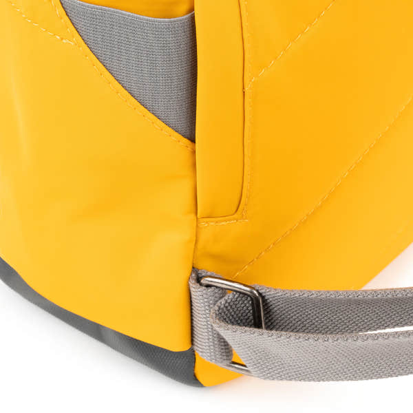 Roka Canfield B Saffron recycled nylon backpack with yellow and gray accents and adjustable strap.