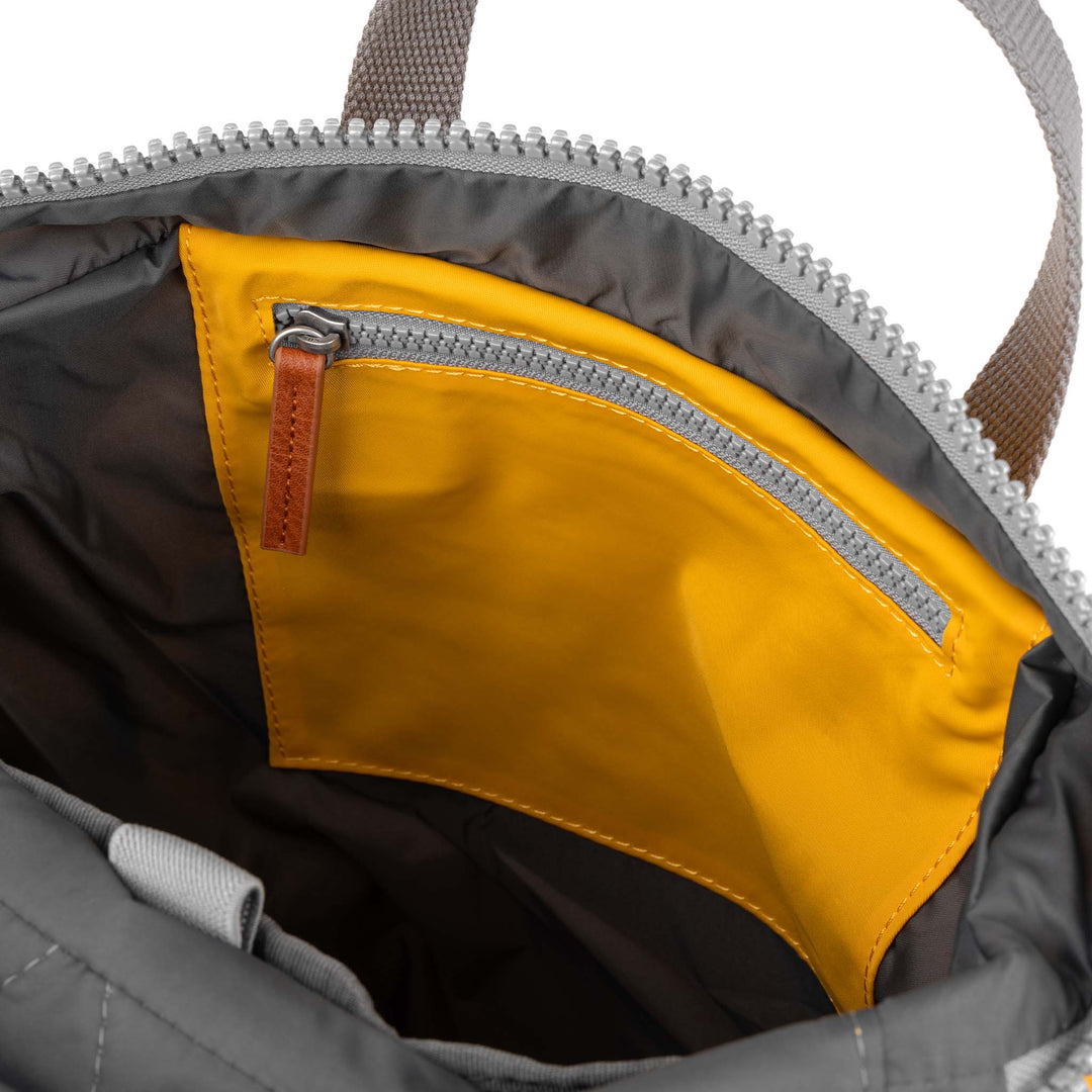 Roka Canfield B Saffron recycled nylon interior pocket with zipper on a gray backpack.