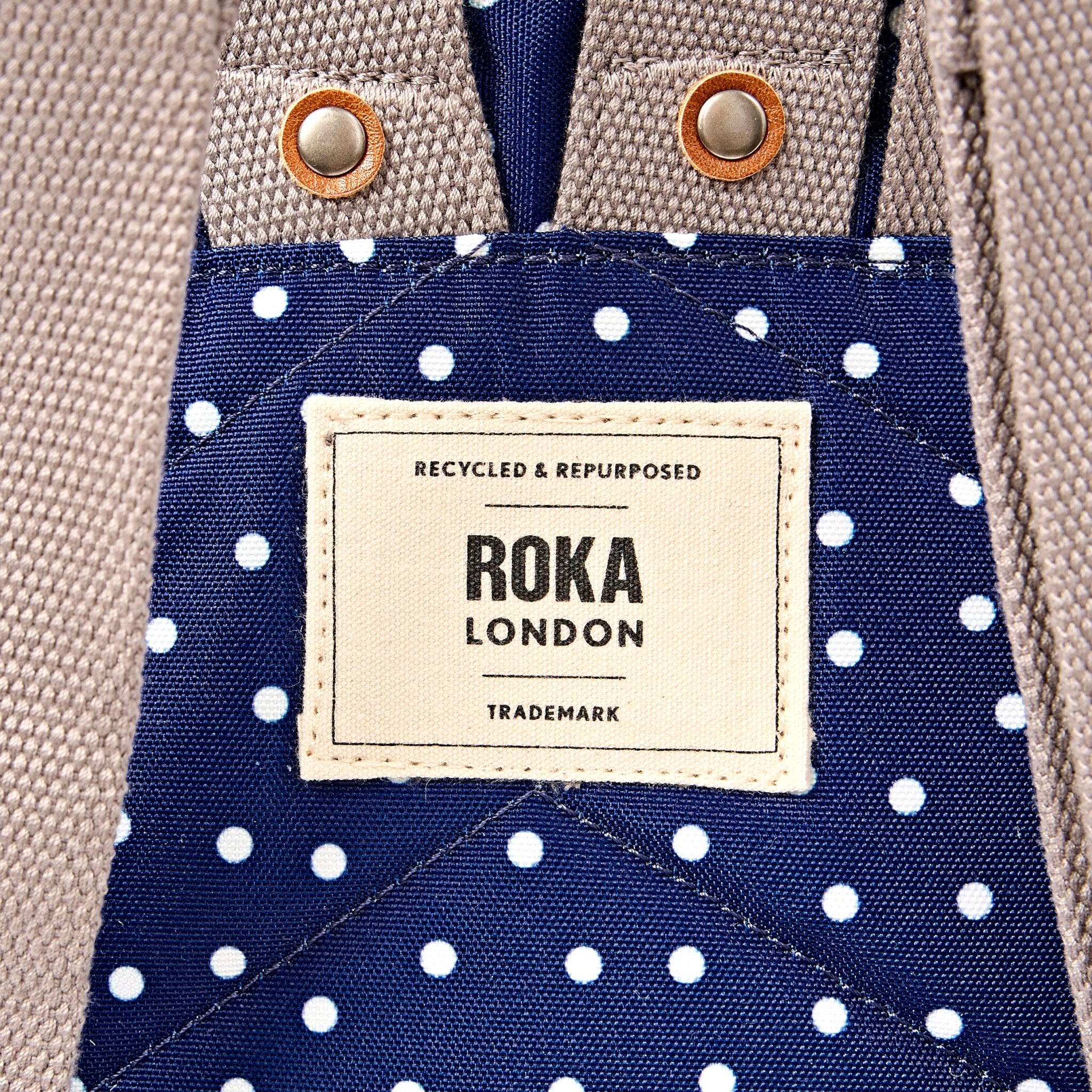 Roka Canfield Small Navy Polka Dot Recycled Canvas Backpack, brand label detail.