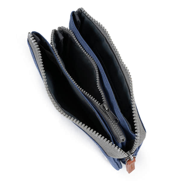 Roka Carnaby Burnt Blue recycled canvas travel wallet with multiple zip compartments and black interior.