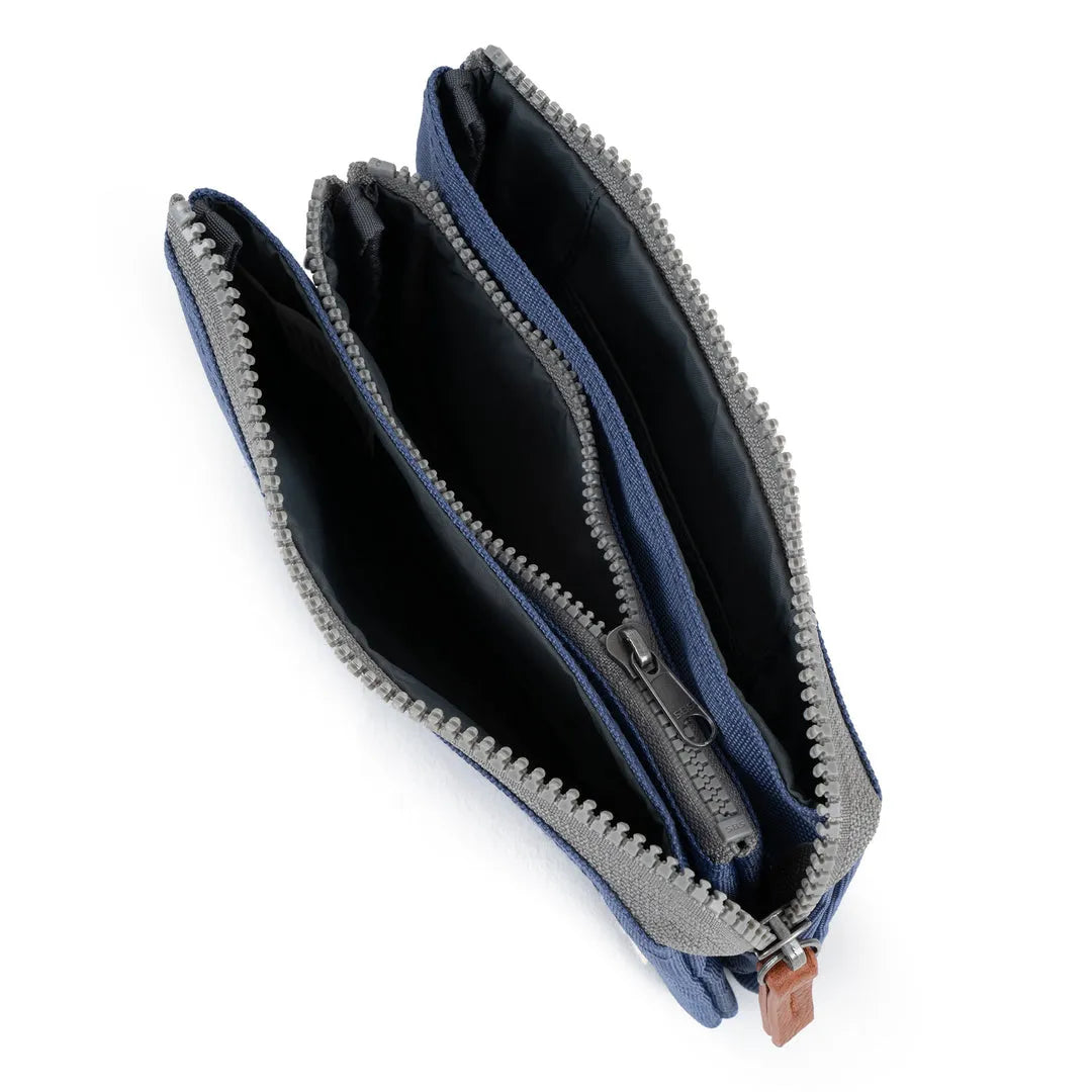 Roka Carnaby Burnt Blue recycled canvas travel wallet with multiple zip compartments and black interior.