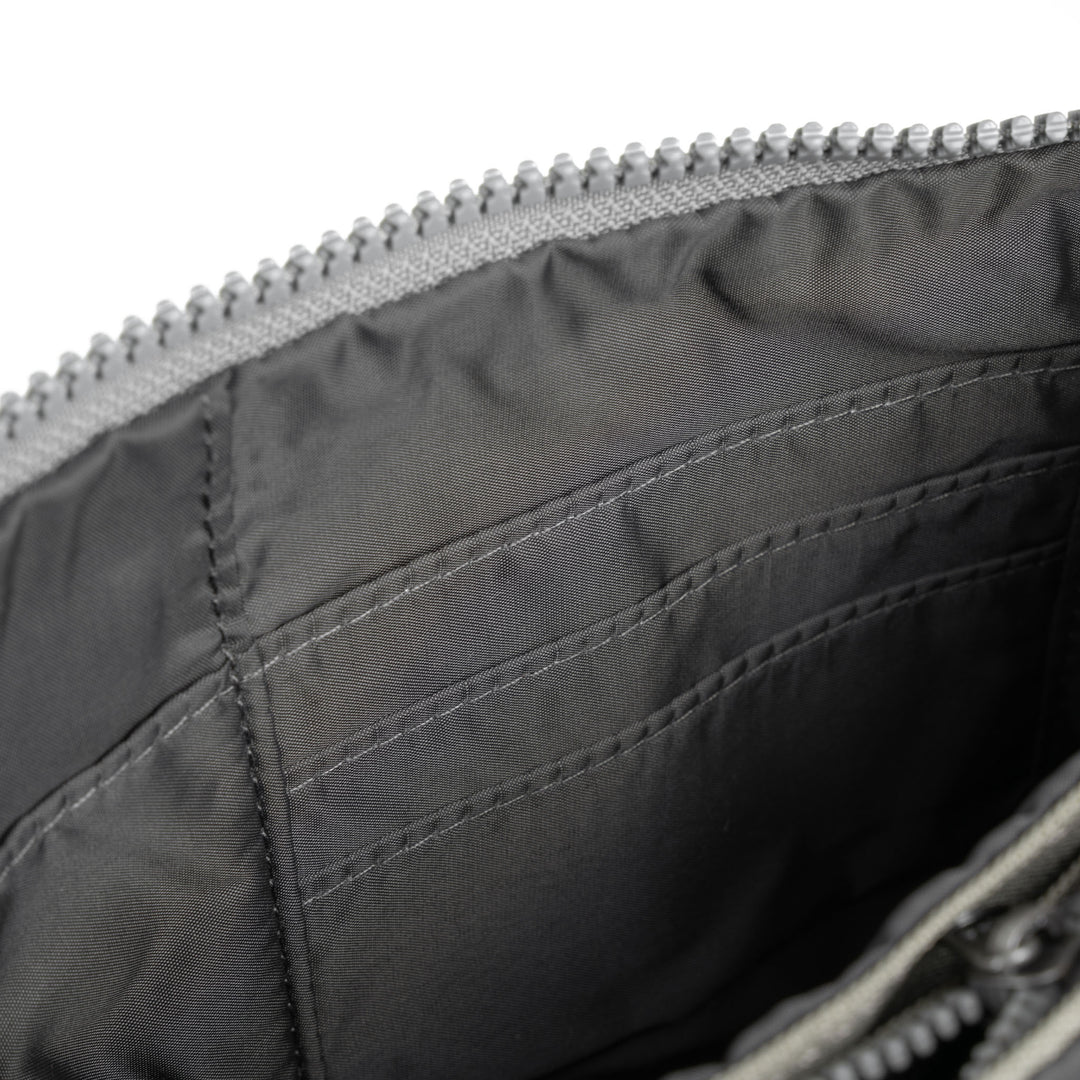 Roka Carnaby Crossbody XL bag in coriander recycled canvas with interior pockets and zip closure.