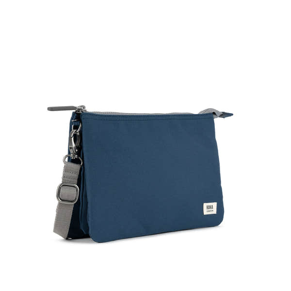 Roka Carnaby Crossbody XL bag in deep blue recycled canvas with grey adjustable strap and silver hardware.
