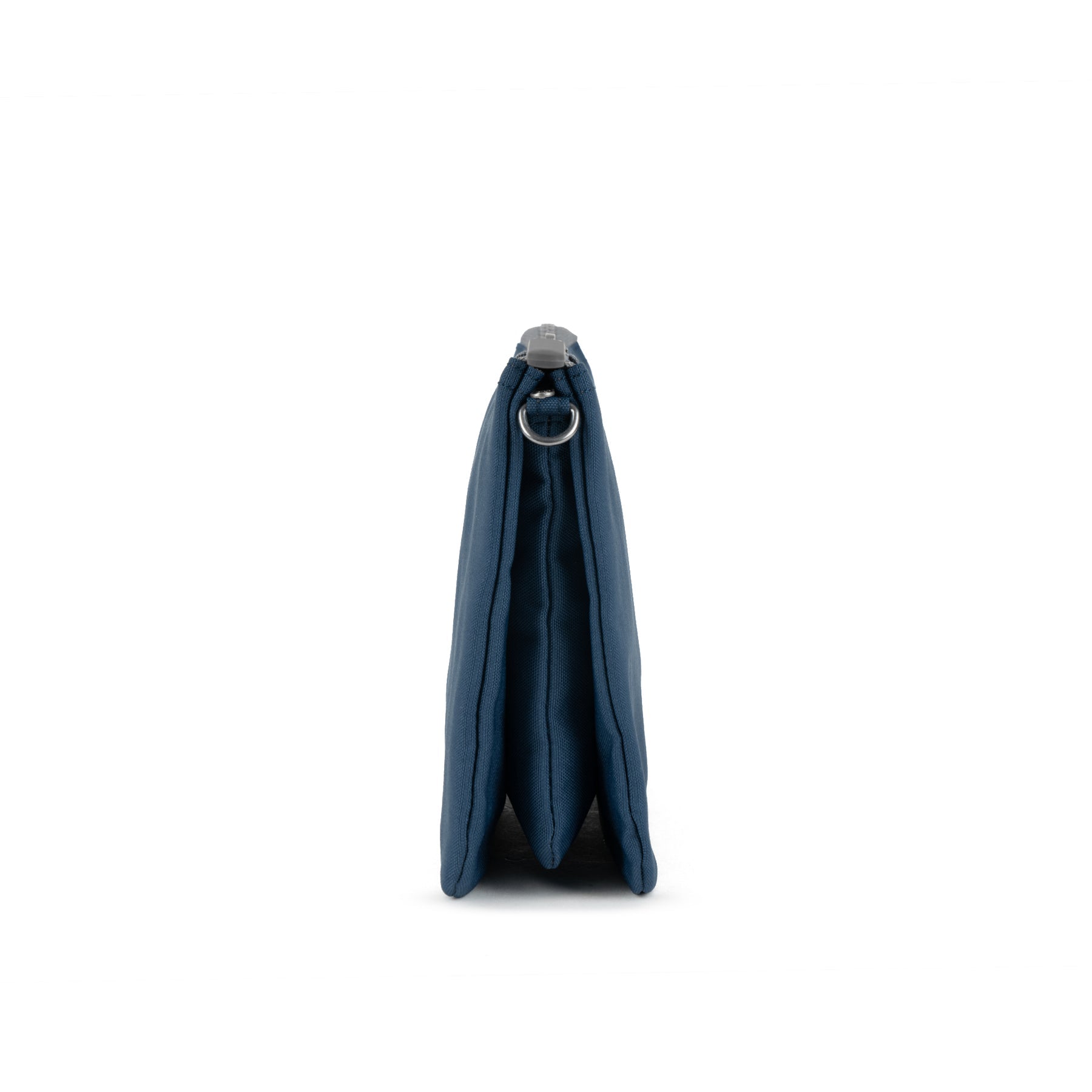 Roka Carnaby Crossbody XL, deep blue recycled canvas bag, side view showing zip closure and metal ring detail.