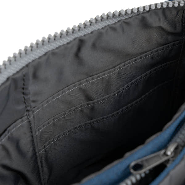 Interior of Roka Carnaby XL Crossbody Bag in deep blue recycled canvas with multiple organizational pockets.