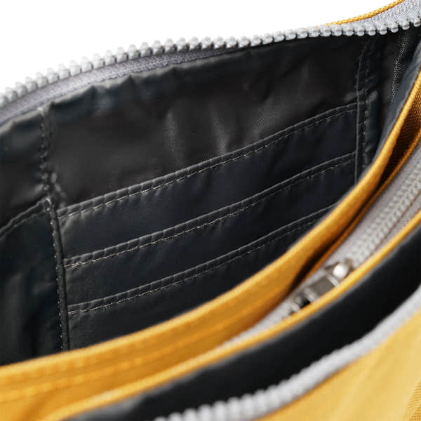 Roka Carnaby Crossbody XL bag in flax recycled canvas, with black interior, multiple card slots, and a zippered pocket.