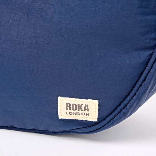 Roka Farringdon Deep Cobalt Recycled Taslon Half Moon Bag, brand label detail.