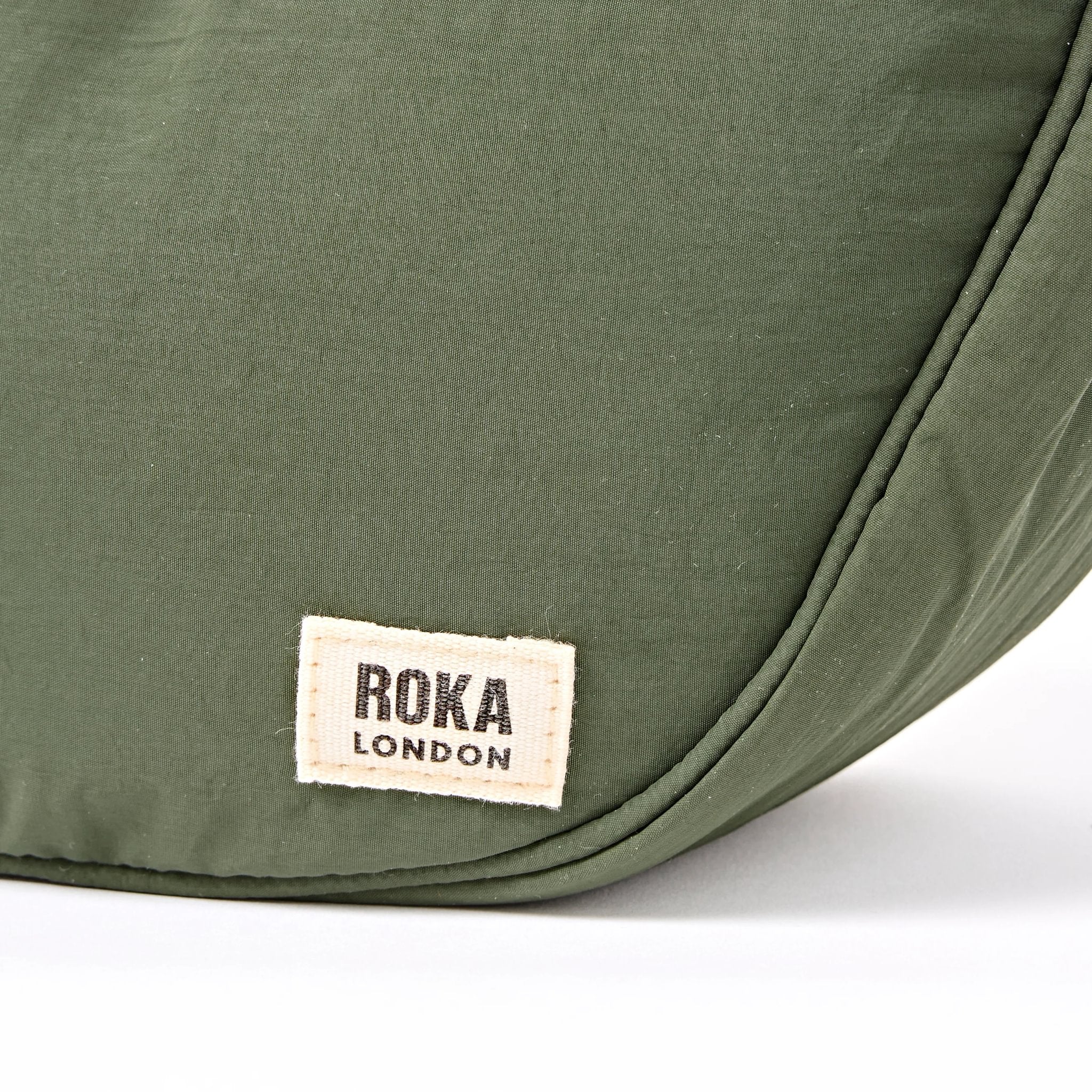 Roka Farringdon Olive Recycled Taslon Half Moon Bag, brand label detail.