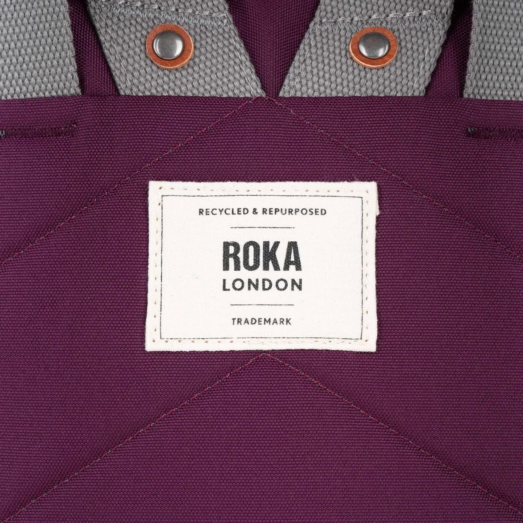 Roka Finchley reusable tote bag with cherry-colored lacquered recycled canvas and gray webbing handles.