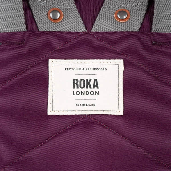Roka Finchley reusable tote bag with cherry-colored lacquered recycled canvas and gray webbing handles.