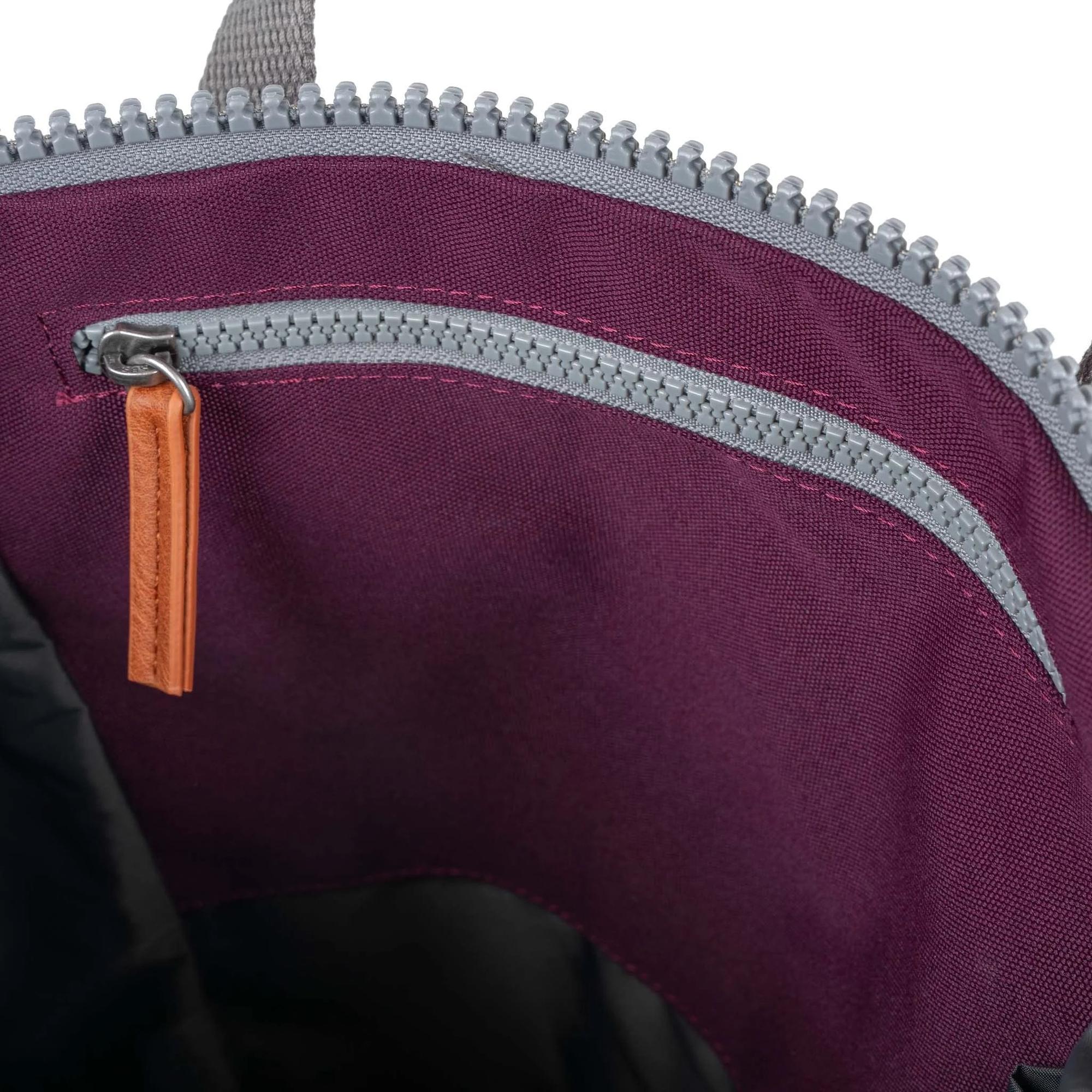 Close-up of Roka Finchley A Cherry Lacquer Recycled Canvas interior with purple lining and silver zipper.