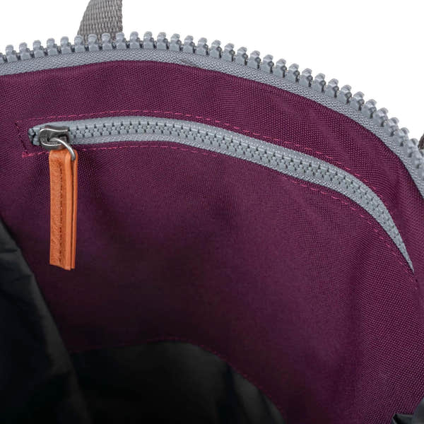 Close-up of Roka Finchley A Cherry Lacquer Recycled Canvas interior with purple lining and silver zipper.